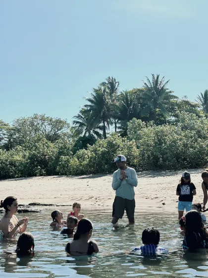 Niñas y niños en una poza escuchando a su guía