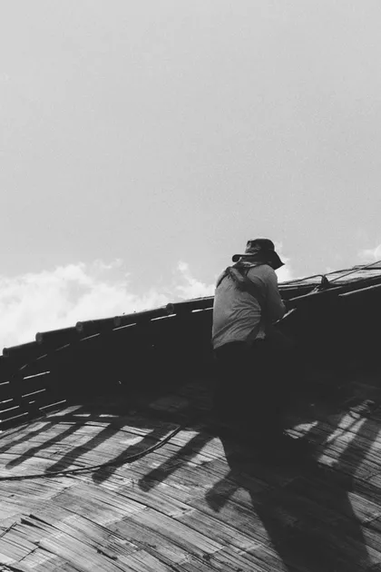 Persona trabajando sobre un techo, en blanco y negro